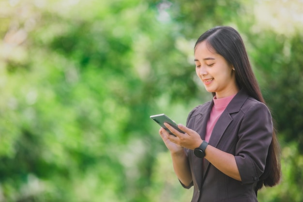 Geschäftsfrau, die am Telefon im Park neben der Stadt steht