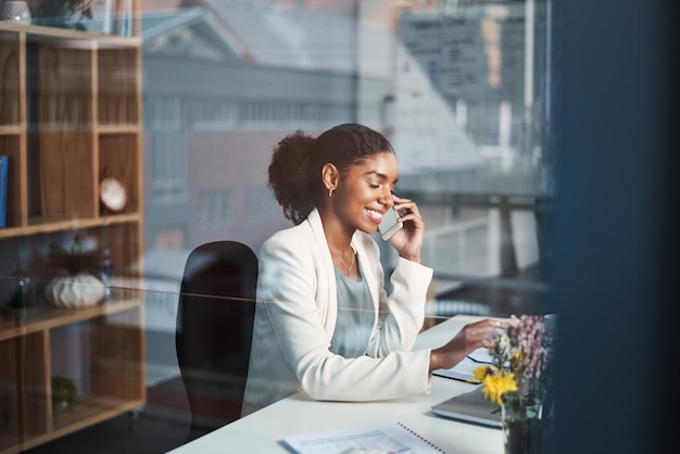 Geschäftsfrau, die am Telefon spricht oder junge Unternehmerin, die gute Nachrichten im Arbeitsbüro erhält Fröhliche schwarze Frau, die lächelt und mit einem Kunden spricht oder Sprachnachrichten in sozialen Medien anhört