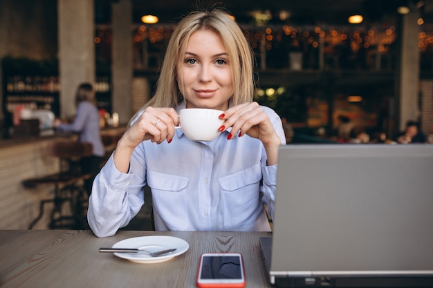 Geschäftsfrau, die an Laptop und Telefon in einem Café arbeitet