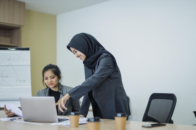 Geschäftsfrau, die auf den Laptop-Bildschirm zeigt, neue Mitarbeiter schult und betreut und zusammenarbeitet