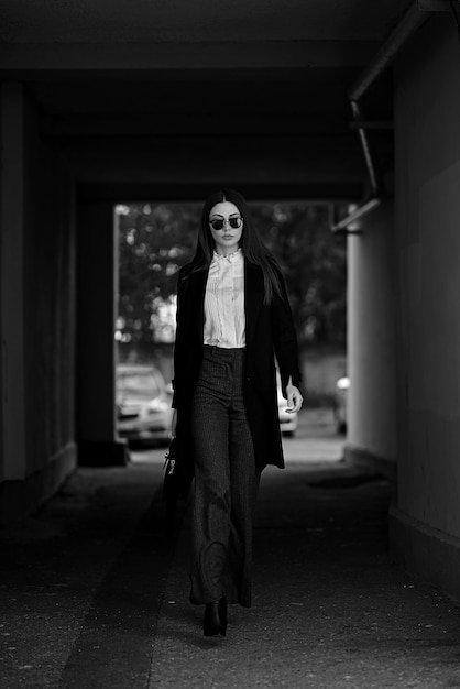 Geschäftsfrau, die auf der Straße mit Sonnenbrille und mit einer Handtasche geht.