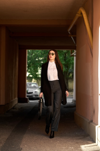Geschäftsfrau, die auf der Straße mit Sonnenbrille und mit einer Handtasche geht.
