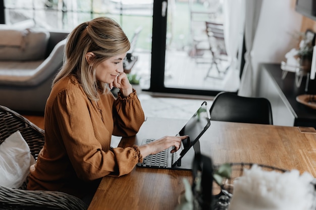 Geschäftsfrau, die auf einem Stuhl sitzt und ihr Geschäft über das Homeoffice verwaltet