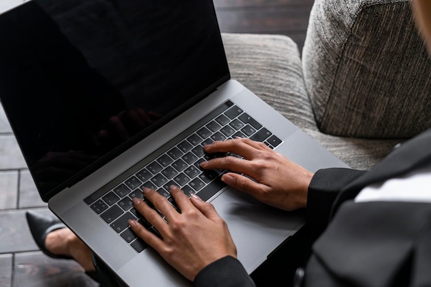 Geschäftsfrau, die auf Laptop im Lehnsessel schreibt