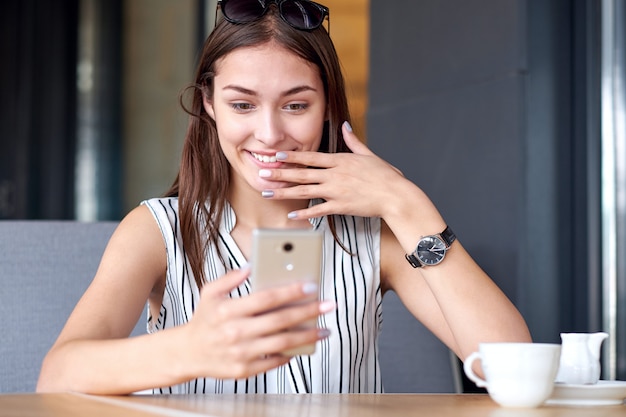 Geschäftsfrau, die Ausdruck überrascht hat, nachdem Mitteilung in der Kaffeestube empfangen worden ist. Wow-Effekt