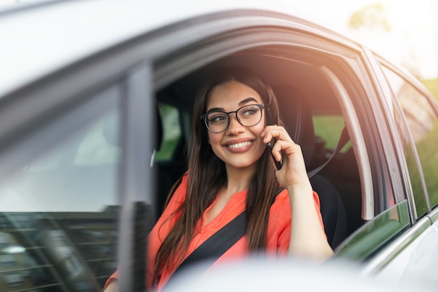 Geschäftsfrau, die Auto fährt und auf Handy sich auf die Straße konzentriert.