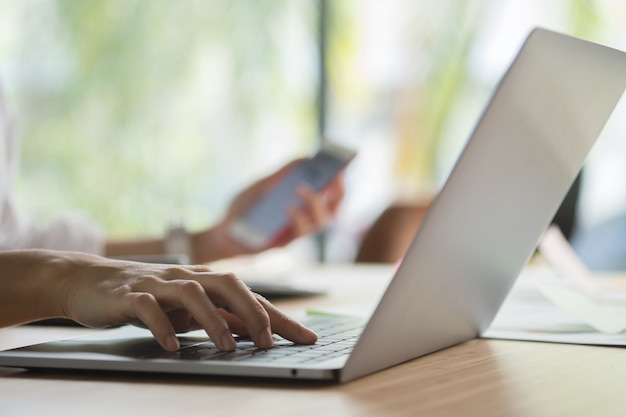 Geschäftsfrau, die Computer am Arbeitsplatz verwendet. Frau arbeitet mit Smartphone