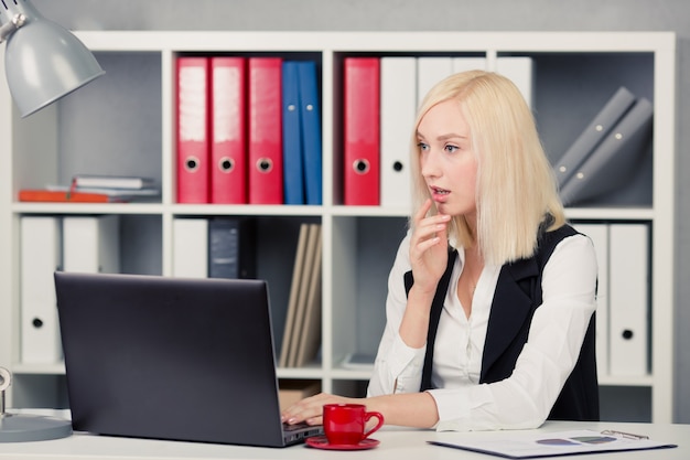 Geschäftsfrau, die Computermonitor im Büro betrachtet