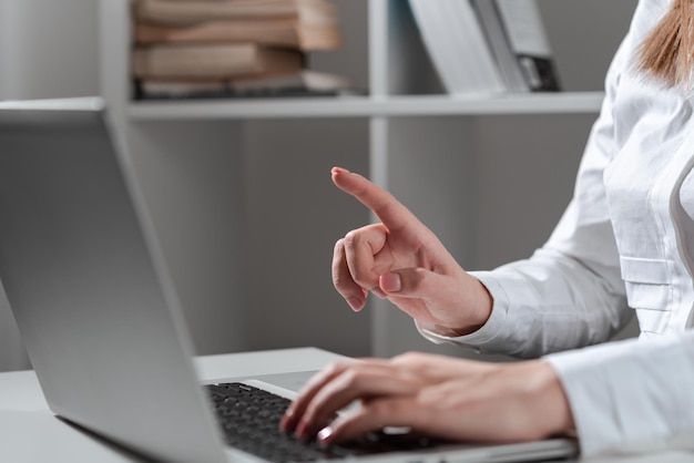 Geschäftsfrau, die die letzten Updates auf der Laptop-Tastatur auf dem Schreibtisch eingibt und wichtige Ideen mit einem Finger zeigt Frau im Büro, die verspätete Nachrichten auf dem Computer schreibt