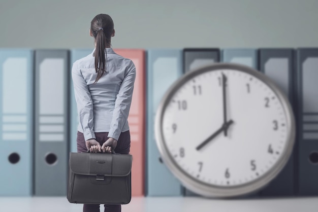 Foto geschäftsfrau, die die zeit auf einer riesigen uhr überprüft