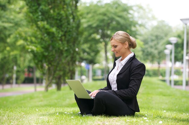 Geschäftsfrau, die draußen an Laptop arbeitet