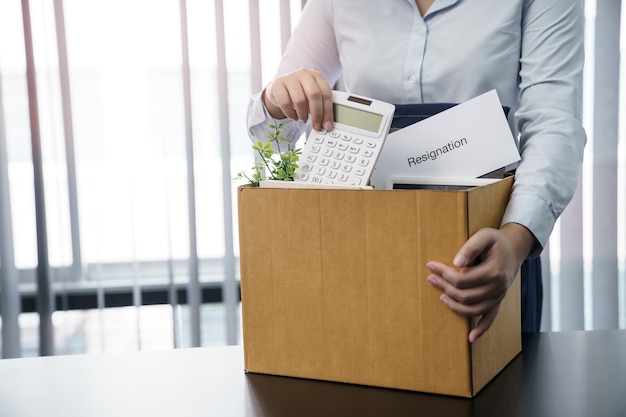 Geschäftsfrau, die ein Kündigungsschreiben sendet und Sachen verpackt