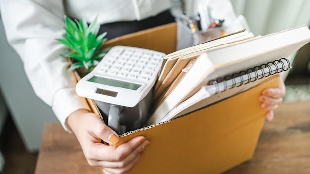 Geschäftsfrau, die ein Kündigungsschreiben sendet und Sachen verpackt