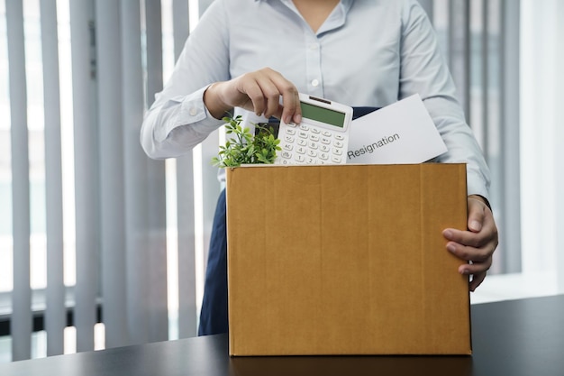 Geschäftsfrau, die ein Kündigungsschreiben sendet und Sachen verpackt