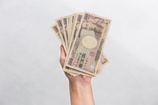 Geschäftsfrau, die Geld gibt und in der Hand 10.000 Geld der japanischen Yen lokalisiert auf Weiß hält