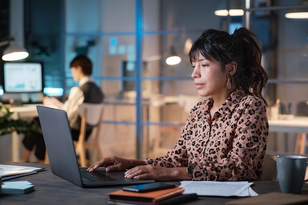 Geschäftsfrau, die im Büro am Laptop arbeitet