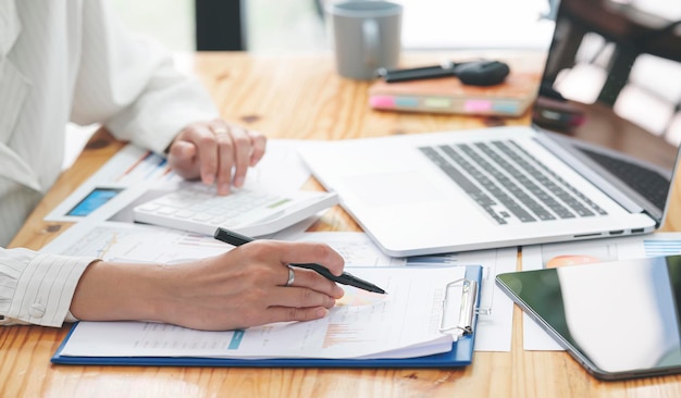 Geschäftsfrau, die im Büro mit Dokument auf ihrem Schreibtisch arbeitet, Planungsanalyse des Finanzberichts, Geschäftsplaninvestition, Finanzanalysekonzept durchführt. Mit Taschenrechner und Tablette.