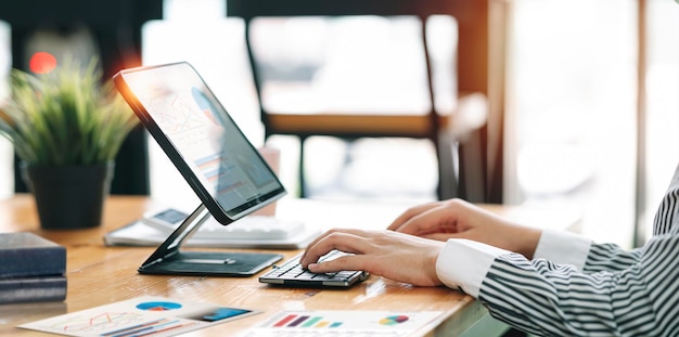 Geschäftsfrau, die im Büro mit einem Dokument auf ihrem Schreibtisch arbeitet und die Planung der Analyse des Finanzberichts, der Investition des Geschäftsplans, des Konzepts der Finanzanalyse durchführt. Mit Laptop und Tablet.