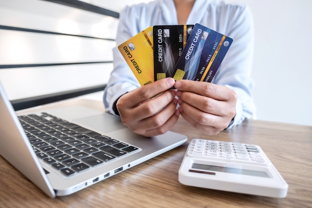 Geschäftsfrau, die Laptop verwendet und Kreditkarte für das Bezahlen der Detailseitenanzeige beim Online-Einkauf hält
