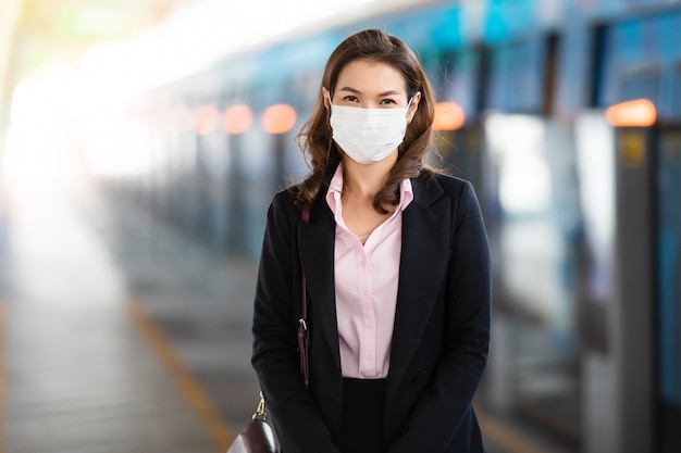 Geschäftsfrau, die Maske trägt, die auf Zug wartet.