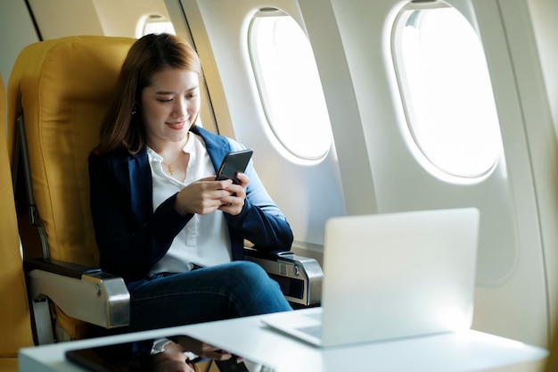 Geschäftsfrau, die mit dem Telefon arbeitet, während sie im Flugzeug sitzt