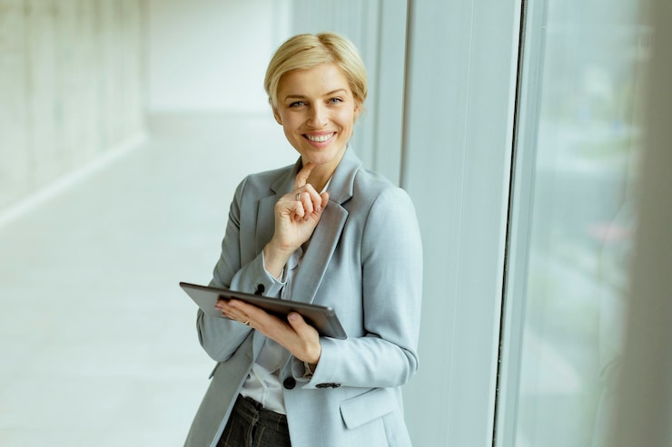 Foto geschäftsfrau, die mit digitalem tablet im bürokorridor steht