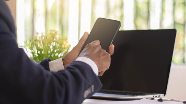 Geschäftsfrau, die mit ihrem Telefon und Laptop arbeitet Glückliche Frau, die Handy beim Arbeiten mit Laptop verwendet