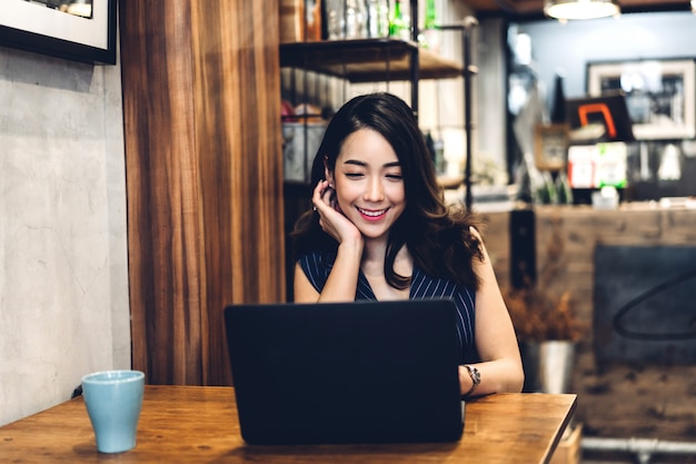 Geschäftsfrau, die mit Laptop-Computer sitzt und arbeitet und Kaffee am Tisch im Café trinkt