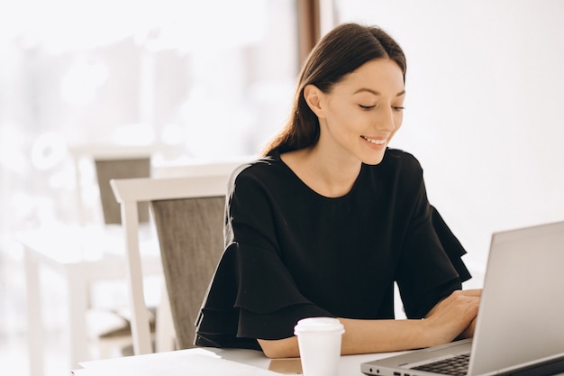 Geschäftsfrau, die mit Laptop in einem weißen Café arbeitet