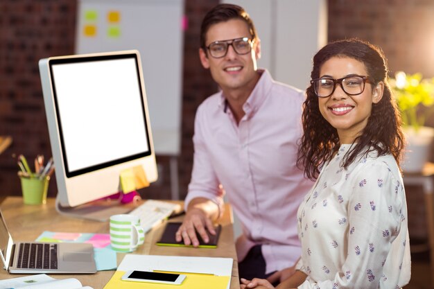 Geschäftsfrau, die mit Mitarbeiter beim Arbeiten am Computer sitzt