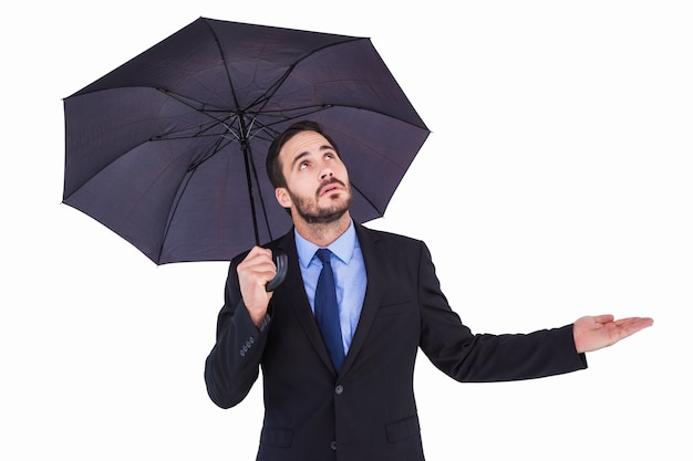 Geschäftsfrau, die Regenschirm beim Prüfen hält, wenn es regnet