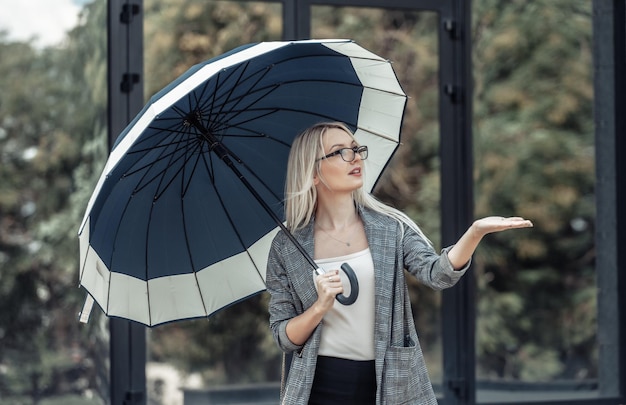 Geschäftsfrau, die Regenschirm hält und Regen überprüft