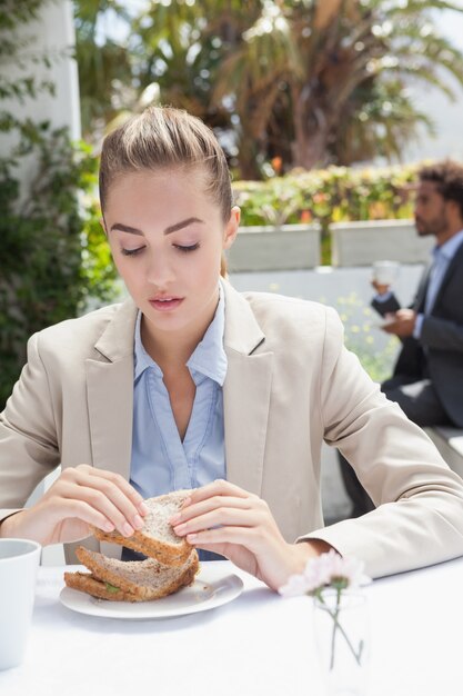 Geschäftsfrau, die Sandwich für das Mittagessen isst