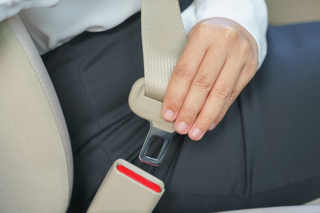 Geschäftsfrau, die Sicherheitsgurt im Auto vor dem Fahren befestigt