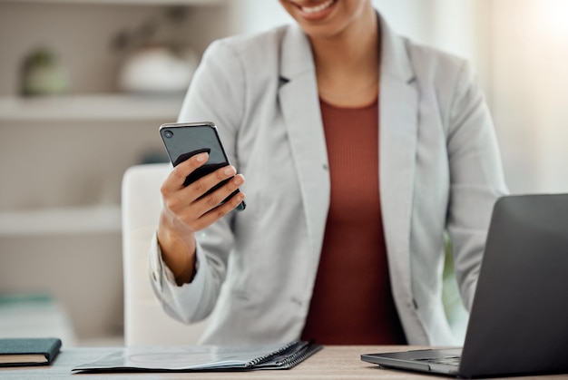 Geschäftsfrau, die SMS durchsucht und eine Benachrichtigung auf ihrem Telefon liest, während sie in den sozialen Medien in einem Büro scrollt
