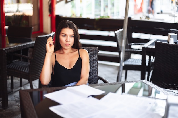 Geschäftsfrau, die über einer Tasse Tee in einem Café sitzt. Unterschrift wichtiger Dokumente. Geschäftstreffen.