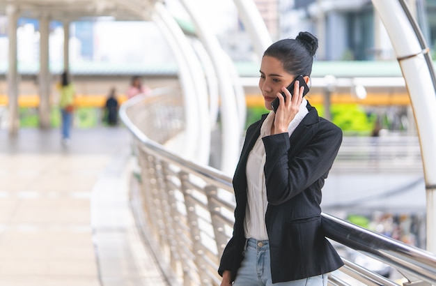 Geschäftsfrau, die um Handy auf Wegart im Freien ersucht