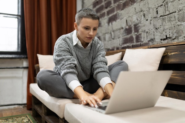 Geschäftsfrau, die von zu Hause aus mit Laptop auf dem Sofa sitzt