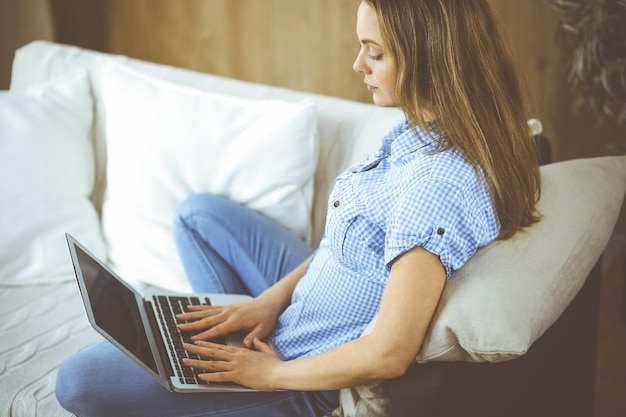 Geschäftsfrau, die während der Covid-19-Quarantäne an einem Laptop arbeitet, der drinnen sitzt. Bleiben Sie während der Coronavirus-Pandemie zu Hause