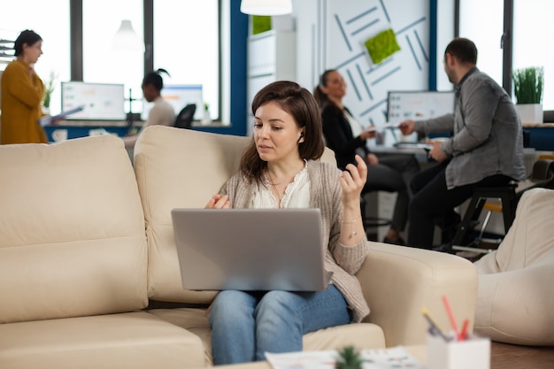 Geschäftsfrau, die während einer Videokonferenz spricht, die vom Laptop auf der Couch aus anruft