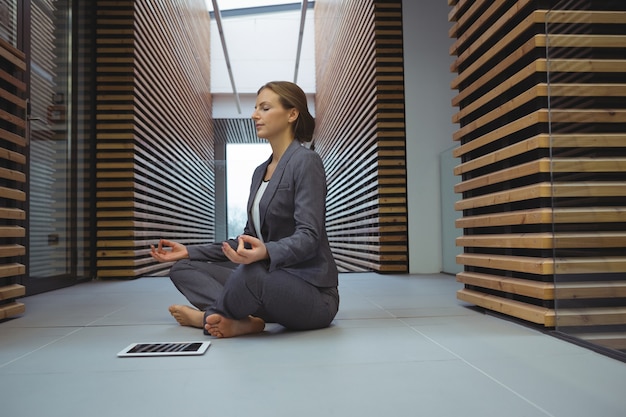 Foto geschäftsfrau, die yoga im korridor durchführt