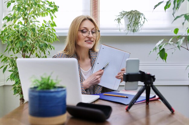 Geschäftsfrau, die zu Hause online mit Laptop und Smartphone arbeitet