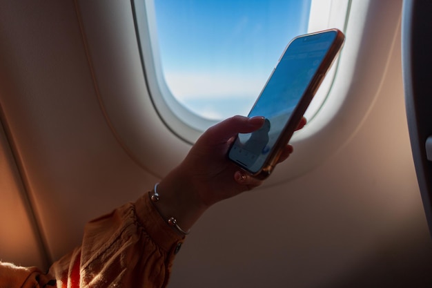 Geschäftsfrau fliegt in einem Flugzeug und verwendet ein Smartphone Reise- und Telefonkonzept