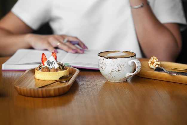 Geschäftsfrau Frühstück im Café Tasse Kaffee mit Schaum und süßen Dessertkuchen