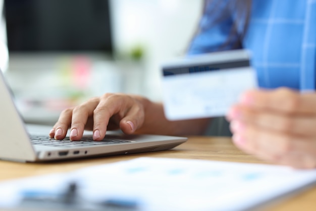 Geschäftsfrau hält Kredit-Plastikkarte und wählt Nummer auf Laptop-Tastatur Online-Zahlungen über