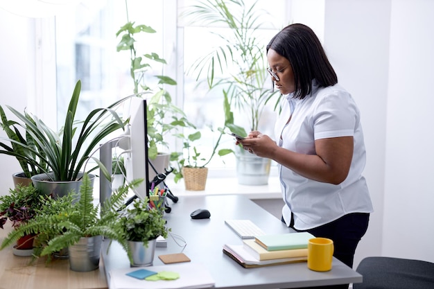 Geschäftsfrau hält Smartphone im Büro, schwarze Managerin, CEO, mit Handy, Handy...