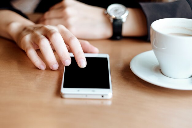 Geschäftsfrau Hände mit Smartphone und Tasse Kaffee. Für die Montage der grafischen Anzeige.