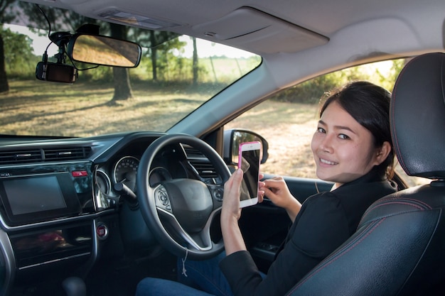 Geschäftsfrau halten ein Smartphone im modernen Auto.