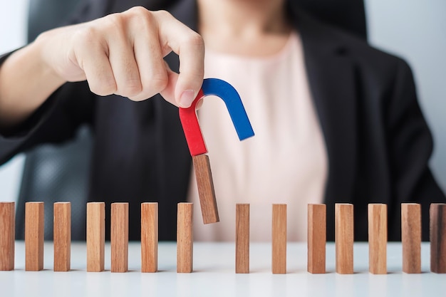 Geschäftsfrau Hand hält Magnet und zieht Mann Holzfigur aus dem Massenblock Business Human Resource Management Rekrutierung Teamwork-Strategie giftige Menschen und Führungskonzepte