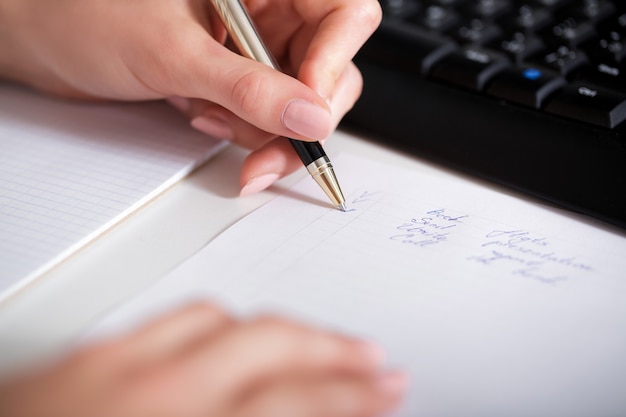 Geschäftsfrau-Handschrift auf Papier. Hand und Notizblock hautnah